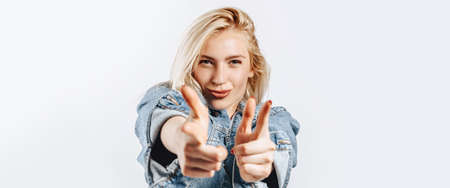 Beautiful young girl fooling around and pointing fingers at screen on gray isolated backgroundの写真素材