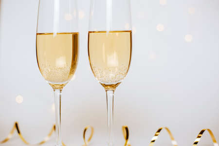 Two glasses of champagne with lights and ribbons on a white background holidayの写真素材
