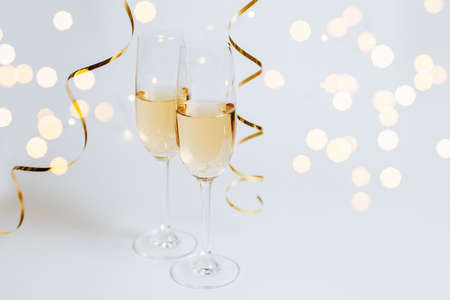 Two glasses of champagne with lights and ribbons on a white background holidayの写真素材