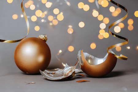 Broken christmas toy to decorate the new year holidays with ribbons and lights on a dark gray backgroundの写真素材