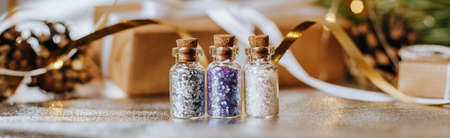 Spangles of gold and silver are scattered from bottles on a white backgroundの写真素材