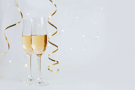 Two glasses of champagne with lights and ribbons on a white background holidayの写真素材
