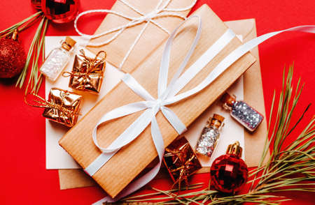 Christmas gift with fir branch and toy on red isolated background. New Year conceptの写真素材