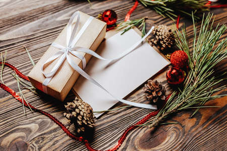 Gift with blank note with fir branch and Christmas toys on wooden background. New Year conceptの写真素材