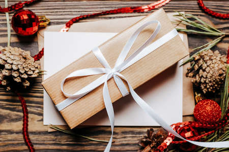 Gift with blank note with fir branch and Christmas toys on wooden background. New Year conceptの写真素材