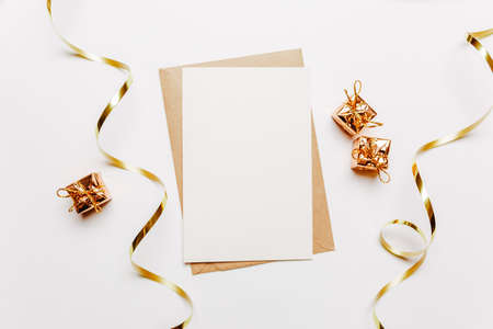 Blank note with envelope, gifts and gold ribbon on white backgroundの写真素材