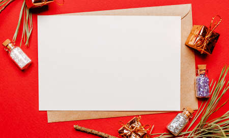 Blank christmas note with gift, fir branch and toy on red isolated background. New Year conceptの写真素材