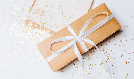 Gift and blank note with envelope, gold glitter stars on white backgroundの写真素材