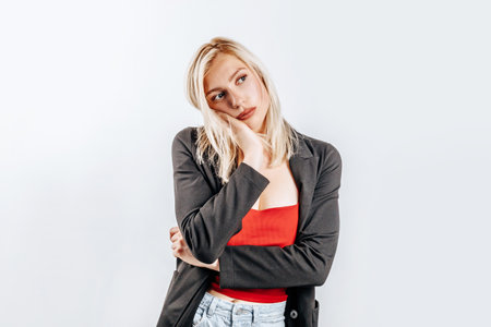 The woman thought about the choice and furrowed her eyebrows. Young beautiful blonde girl holds a hand to the face thinks and makes a decision. Place for advertising. What to chooseの写真素材