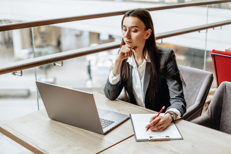 Young girl office worker or business lady signs documents. Concentrated businesswoman working with papers. Business conceptの写真素材
