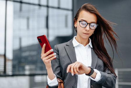 A business woman checks the time in the city during a working day waiting for a meeting. Discipline and timing. An employee goes towards a corporate meeting.の写真素材