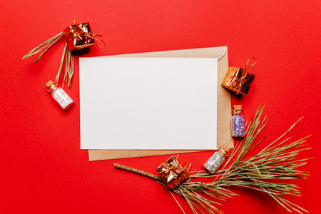 Blank christmas note with gift, fir branch and toy on red isolated background. New Year conceptの写真素材
