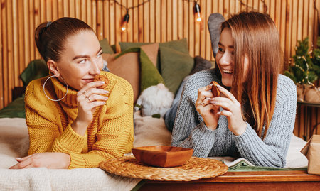 Two beautiful cheerful happy young girls girlfriend give Christmas gifts on the background of a new year tree at homeの写真素材