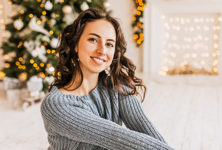 Beautiful cheerful happy young girl with christmas gifts on the background of a new year tree at homeの写真素材