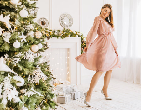 Beautiful cheerful happy young girl with christmas gifts on the background of a new year tree at homeの写真素材