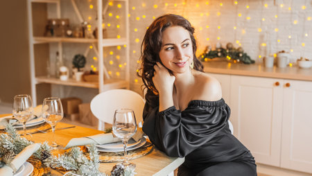 Two beautiful cheerful happy young girls friend laughing at the christmas dining table on the background of the new year kitchenの写真素材