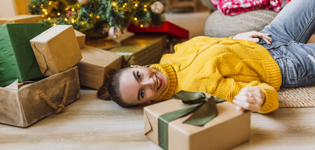 Beautiful cheerful happy young girl with christmas gifts on the background of a new year tree at homeの写真素材