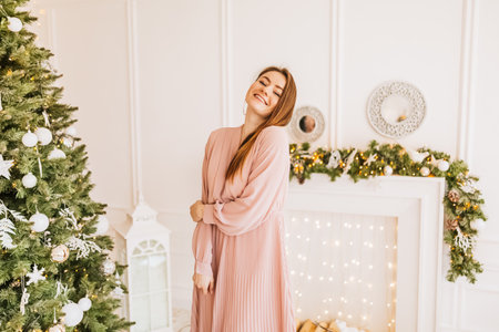Beautiful cheerful happy young girl with christmas gifts on the background of a new year tree at homeの写真素材