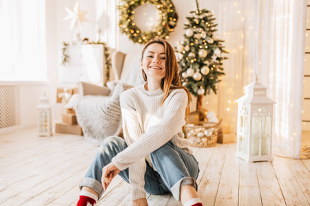 Beautiful cheerful happy young girl with christmas gifts on the floor near the new year tree at homeの写真素材