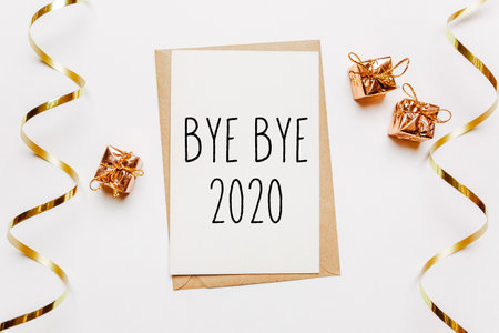 bye bye 2020 note with envelope, gifts and gold ribbon on white background. merry christmas and New Year conceptの写真素材