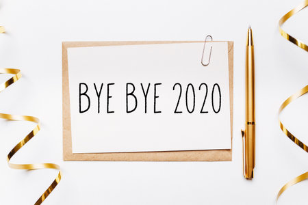 bye bye 2020 note with envelope, pen, gifts and gold ribbon on white background. merry christmas and New Year conceptの写真素材