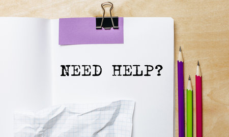 Need Help text written on a paper with pencils on the desk in the officeの写真素材