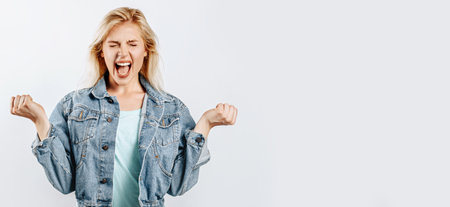 Beautiful young girl unhappy frowning and shouting on gray isolated backgroundの写真素材