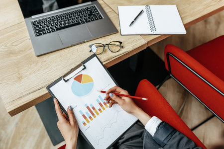 Business woman checks charts and refreshes financial progress. The girl analyzes the business model in the workplace.の写真素材