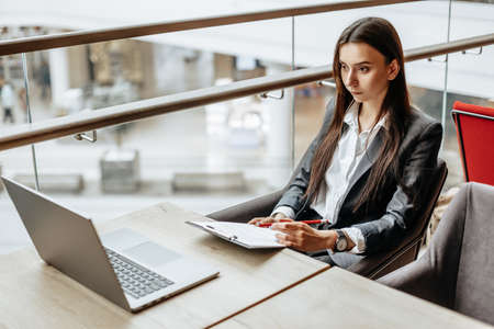 Young girl office worker or business lady signs documents. Concentrated businesswoman working with papers. Business conceptの写真素材