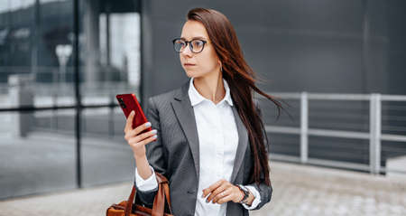 A business woman checks the time in the city during a working day waiting for a meeting. Discipline and timing. An employee goes towards a corporate meeting.の写真素材