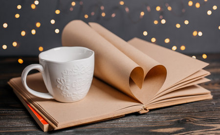 Heart made from book sheets with a cup, love and valentine concept on a wooden tableの写真素材