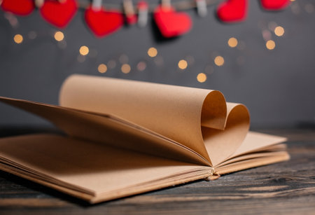 Heart made from book sheets in lights, love and valentine concept on a wooden tableの写真素材