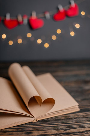 Heart made from book sheets in lights, love and valentine concept on a wooden tableの写真素材