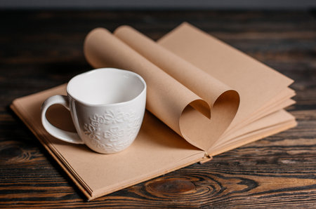 Heart made from book sheets with a cup, love and valentine concept on a wooden tableの写真素材