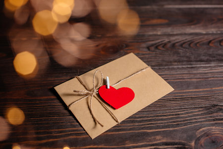 Love letter with a heart on a background of lights, love and valentine concept on a wooden tableの写真素材