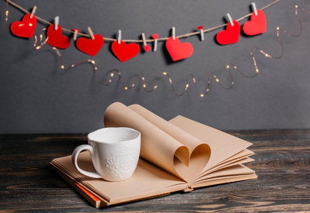 Heart made from book sheets with a cup, love and valentine concept on a wooden tableの写真素材