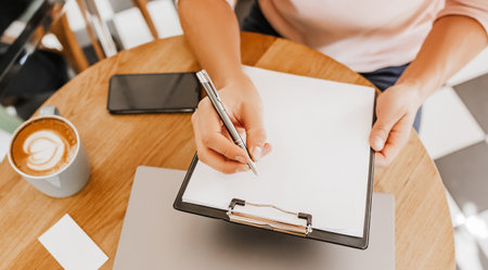 Man writes business information in notebook at workplace in office with laptopの写真素材