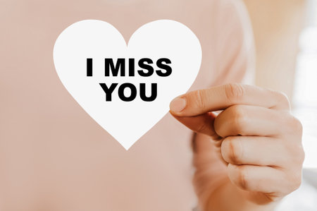 Man holding a love card in the shape of a heart with I miss youの写真素材
