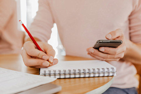 Man writes business information in notebook at workplace in office with smartphoneの写真素材