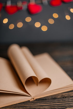 Heart made from book sheets in lights, love and valentine concept on a wooden tableの写真素材