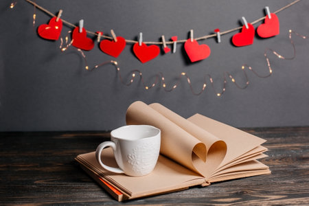 Heart made from book sheets with a cup, love and valentine concept on a wooden table