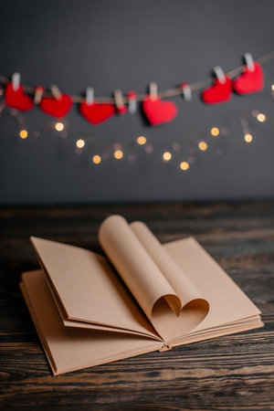 Heart made from book sheets in lights, love and valentine concept on a wooden tableの写真素材