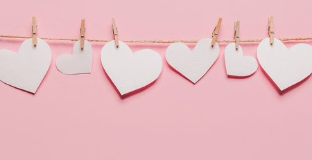 white heart pin on a rope on isolated pink background, love and valentine conceptの写真素材