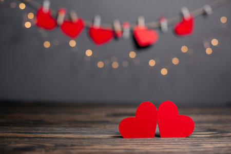 pair of red hearts on lights background, love and valentine concept on a wooden tableの写真素材