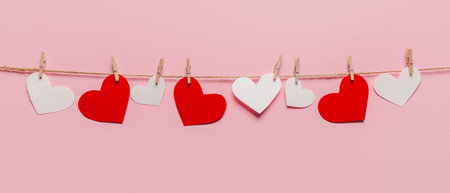 white and red heart pin on a rope on isolated pink background, love and valentine conceptの写真素材