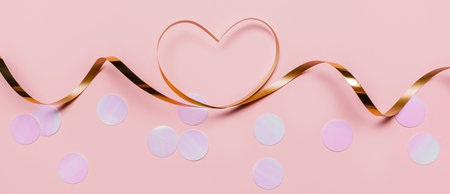 shape heart by gold ribbon on isolated pink backgroundの写真素材