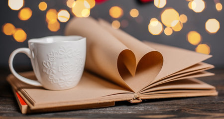 Heart made from book sheets with a cup, love and valentine concept on a wooden tableの写真素材