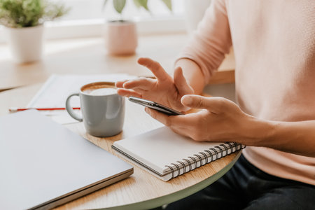 Man writes business information in notebook at workplace in office with smartphoneの写真素材