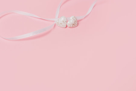 shape heart with wihte ribbon on isolated pink backgroundの写真素材