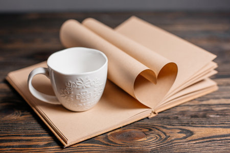 Heart made from book sheets with a cup, love and valentine concept on a wooden tableの写真素材